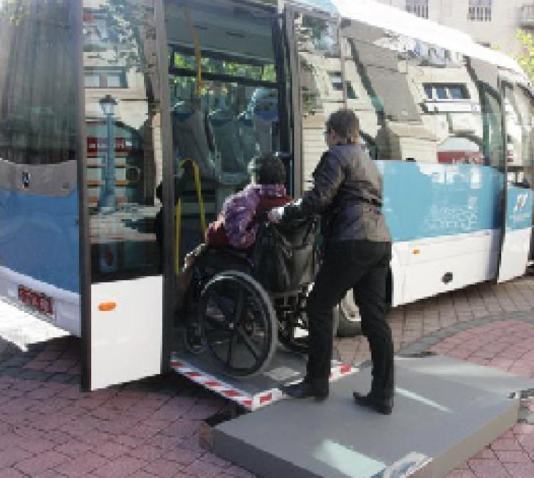 Persona empujando silla de ruedas para entrar al bus